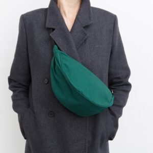 Green canvas half moon bag worn crossbody over a grey coat
