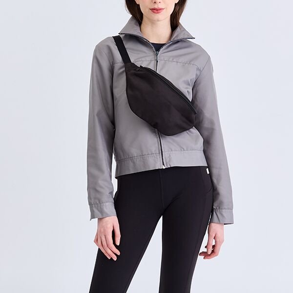 Black canvas half moon crossbody bag worn over a grey jacket
